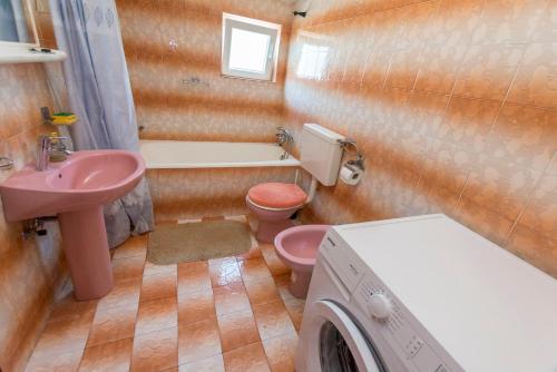 a bathroom with a pink sink and a washing machine at Apartments Jere Proto in Primošten
