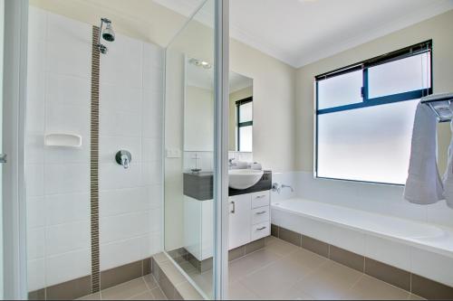 a bathroom with a tub and a sink and a shower at A Little Luxury in Town in Dunsborough