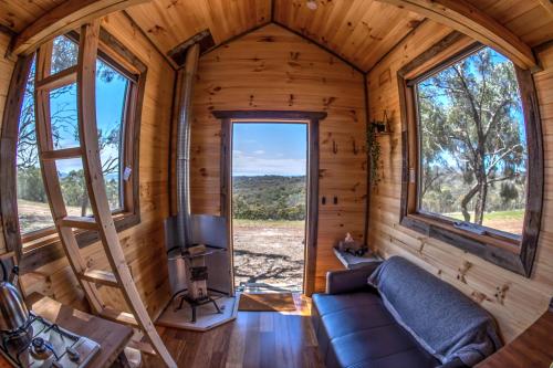 ein Wohnzimmer in einem Baumhaus mit einem großen Fenster in der Unterkunft Hilltop Tiny House in Tallarook
