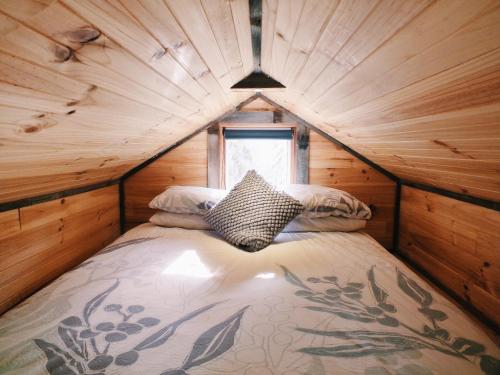 Bett in einer Holzhütte mit Fenster in der Unterkunft Hilltop Tiny House in Tallarook