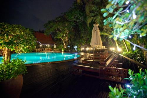 a swimming pool at night with a closed umbrella at Kamala Beach Estate Resort - SHA Extra Plus in Kamala Beach