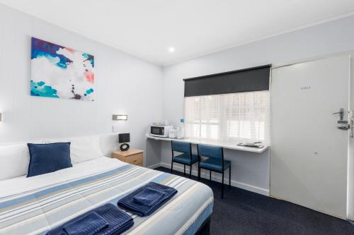 1 dormitorio con cama, escritorio y mesa en Wattle Grove Motel Maryborough en Maryborough