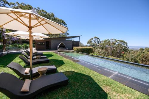an outdoor pool with lounge chairs and an umbrella at Spicers Sangoma Retreat - Adults Only in Kurrajong