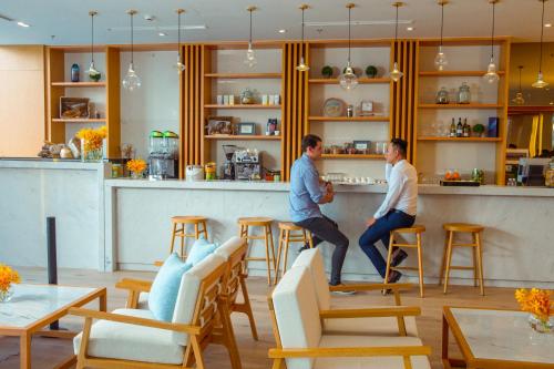 two men standing at a bar in a restaurant at TMS Hotel Da Nang Beach in Da Nang