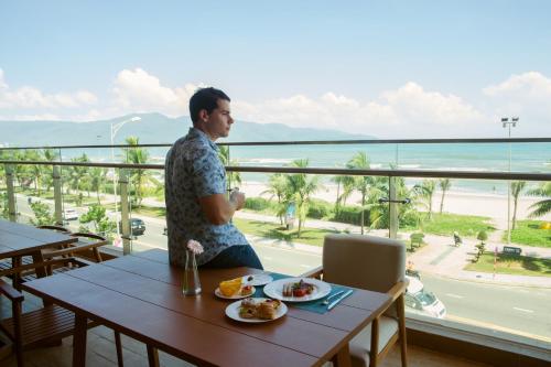 a man sitting at a table with a plate of food at TMS Hotel Da Nang Beach in Da Nang