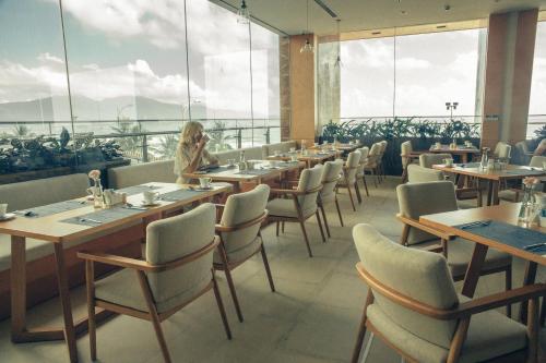 a woman sitting at a table in a restaurant at TMS Hotel Da Nang Beach in Da Nang
