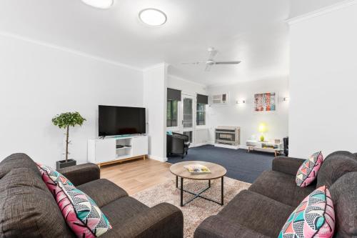 a living room with two couches and a tv at Wattle Grove Motel Maryborough in Maryborough