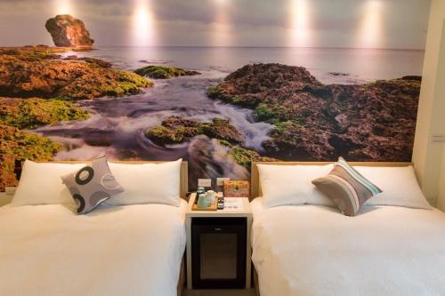 twee bedden in een kamer met een schilderij van de oceaan bij Tiangong Super Inn homestay in Hengchun