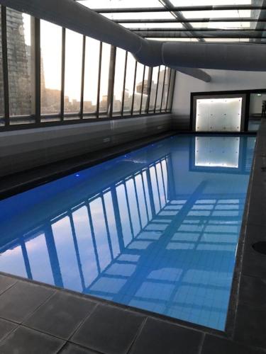a large swimming pool in a building with windows at EPIC Private Apartment in Melbourne