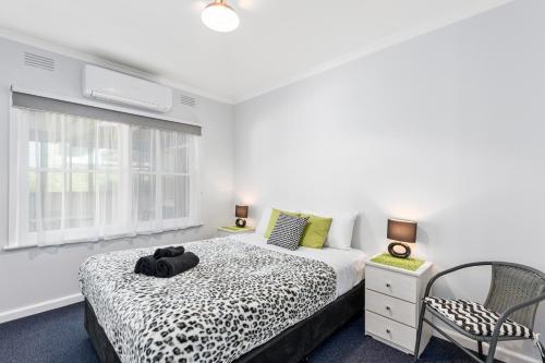 a bedroom with a bed and a chair and a window at Wattle Grove Villa in Maryborough