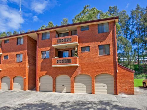 a red brick building with four white garage doors at Waves Appartment in Kiama