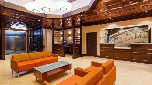 a lobby with orange couches and a table in a building at Best Western Plus Waltham Boston in Waltham