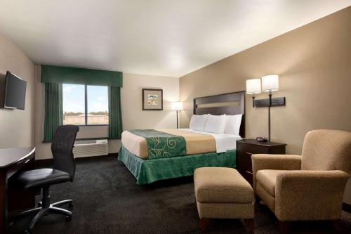 a hotel room with a bed and a desk and chairs at Baymont by Wyndham Glendive in Glendive