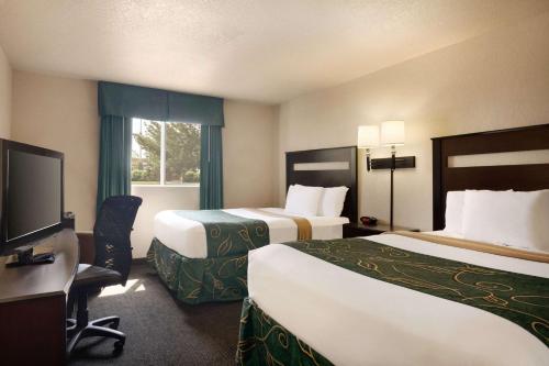 a hotel room with two beds and a flat screen tv at Travelodge by Wyndham Jefferson City in Jefferson City