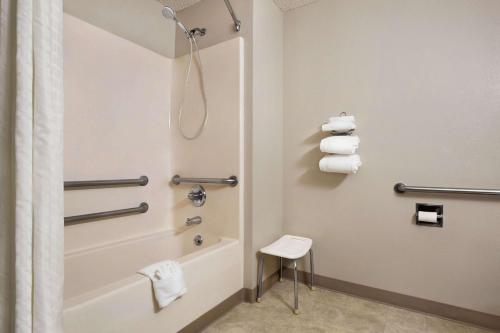 a bathroom with a shower and a tub and a stool at Super 8 by Wyndham Lincoln North in Lincoln