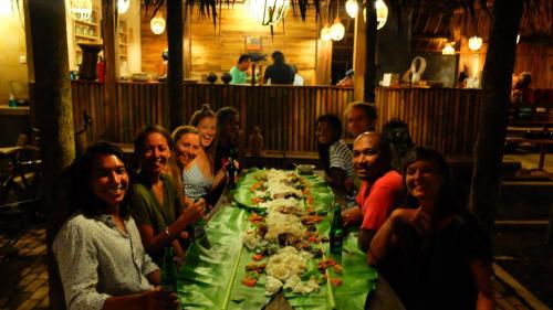 a group of people sitting around a table with a long table at Villa Monyet Java in Batukaras