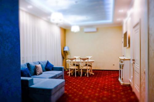sala de estar con sofá azul y mesa en Lazurny Bereg Hotel, en Tyumen