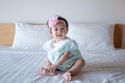 a little girl sitting on a bed at Get Zleep Premium Budget Hotel in Chiang Mai