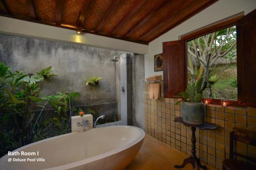 uma casa de banho com uma banheira e uma janela em Ubud Syailendra Heritage Villas by EPS em Ubud