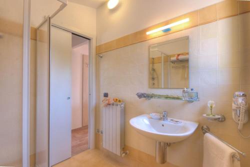 ein Bad mit einem Waschbecken, einem Spiegel und einer Dusche in der Unterkunft Le Fiabe Hotel Resort in Numana