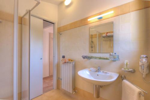 Un baño con lavabo, espejo y ducha. en Le Fiabe Hotel Resort, en Numana