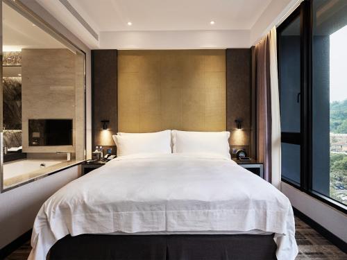 a bedroom with a large bed and a large window at The Tango Hotel Taipei Jiantan in Taipei