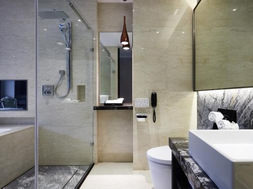 a bathroom with a shower and a toilet and a sink at The Tango Hotel Taipei Jiantan in Taipei