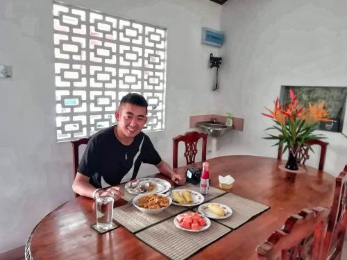 a man sitting at a table with plates of food at Old Parkland Hostel in Galle