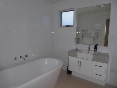 a white bathroom with a tub and a sink at Bridport Horizon Views in Bridport