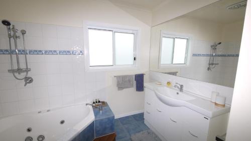 a white bathroom with a tub and a sink at Position on Alexander in Bridport