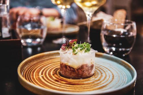 a dessert on a plate on a table with wine glasses at Hotel Pommern in Mariehamn