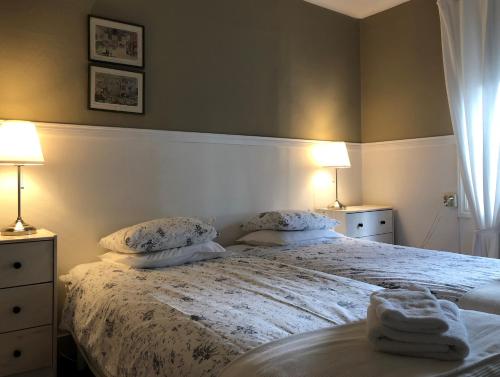 a bedroom with a bed with two lamps and towels on it at Hotel PerOlofGården in Åsbro