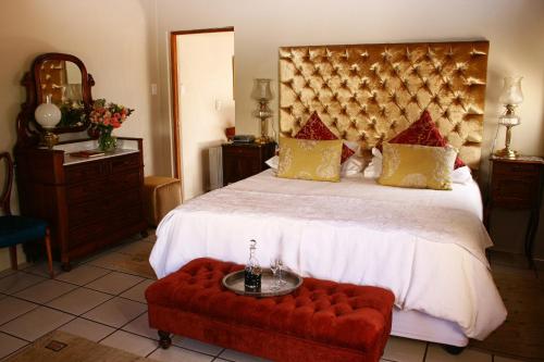 a bedroom with a large bed and a red bench at Rietfontein Ostrich Palace in Vleirivier