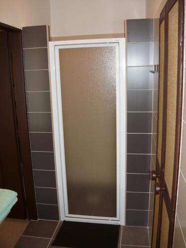 a shower door in a bathroom with gray tiles at Kotrba privat in Telč