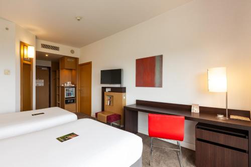 a hotel room with a bed and a desk with a red chair at Novotel Trabzon in Trabzon