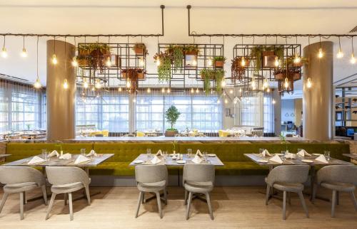 a dining room with tables and chairs and chandeliers at Novotel Trabzon in Trabzon