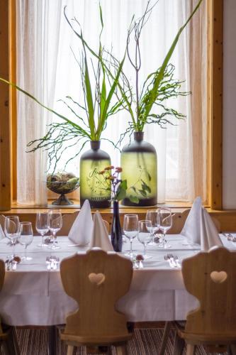 a table with glasses and plants in vases at Sporthotel Pontresina in Pontresina