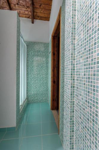 a bathroom with green tiled walls and a window at Liuba Houses in Vasilikos