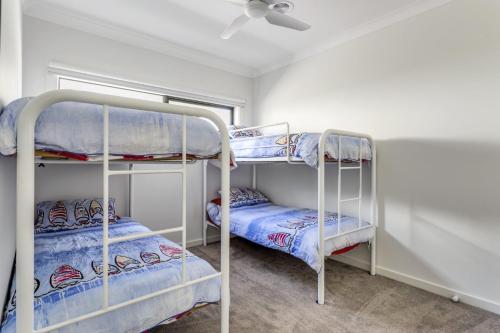 two bunk beds in a room with a ceiling at Diamond Bay Beach House: brand new in Sorrento