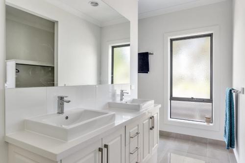 a white bathroom with two sinks and a mirror at Diamond Bay Beach House: brand new in Sorrento