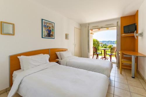 2 Betten in einem Hotelzimmer mit Balkon in der Unterkunft Azureva Hendaye in Hendaye