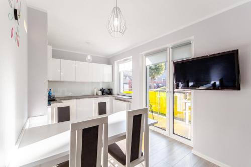 a kitchen with white cabinets and a flat screen tv at Kolorowe Balkony II by Renters in Międzyzdroje