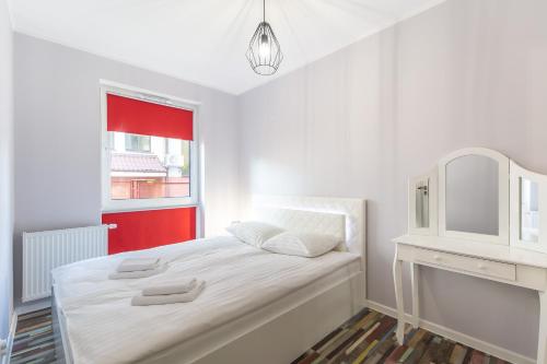 a white bedroom with a white bed and a window at Kolorowe Balkony II by Renters in Międzyzdroje