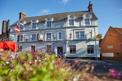 a white building on a street with flowers in front at Best Western The George Hotel, Swaffham in Swaffham