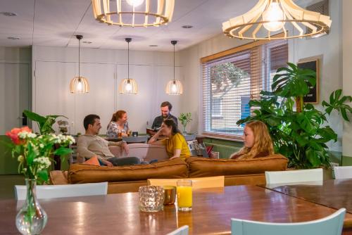 a group of people sitting around a table in a room at Stayokay Hostel Arnhem in Arnhem