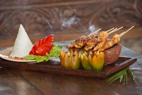 a plate of food with meat and vegetables on a tray at Hotel Pondok Sari Beach & SPA Resort in Pemuteran