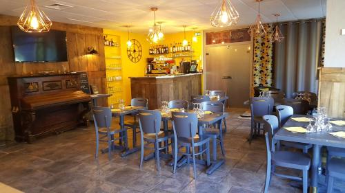 a restaurant with tables and chairs and a piano at Hôtel Le Square in Aurillac