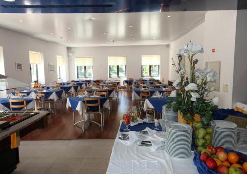 a banquet hall with tables and chairs with blue tables and flowers at INATEL Caparica in Costa da Caparica
