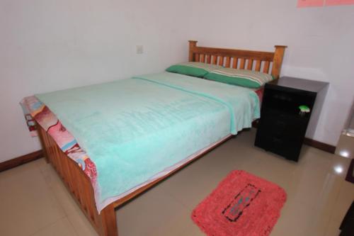 a bedroom with a bed and a red rug at Narra Homestay in Maskeliya