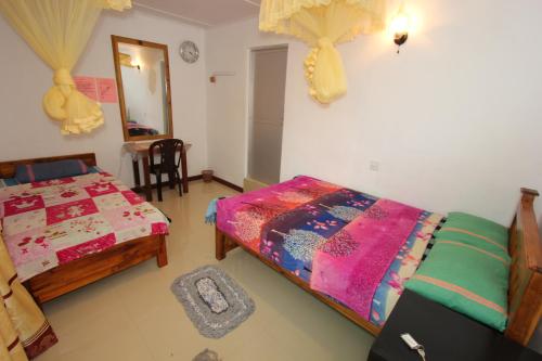 a bedroom with two beds and a mirror at Narra Homestay in Maskeliya